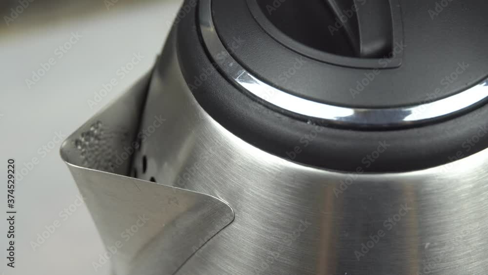 boiling water in an electric kettle, steam escapes from the spout of