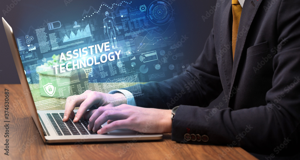 Businessman working on laptop with ASSISTIVE TECHNOLOGY inscription, cyber technology concept Businessman working on laptop with ASSISTIVE TECHNOLOGY inscription, cyber technology concept