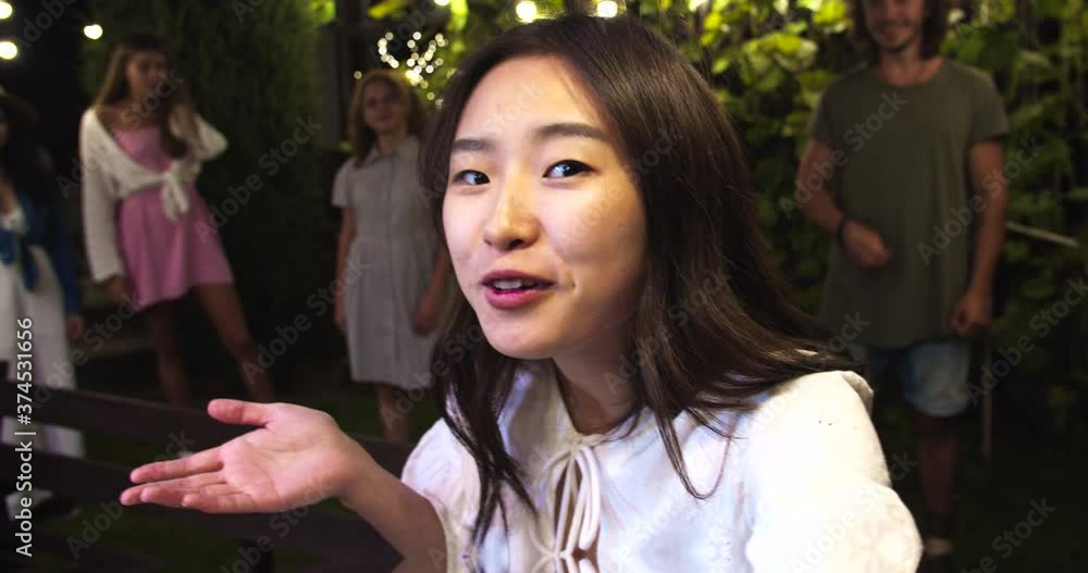 POV of happy Asian girl talking in good mood. Pretty African American and Caucasian girls waving hands. Handsome joyful males smiling. Mixed-races youth at garden party in evening. Talk concept POV of happy Asian girl talking in good mood. Pretty African American and Caucasian girls waving hands. Handsome joyful males smiling. Mixed-races youth at garden party in evening. Talk concept