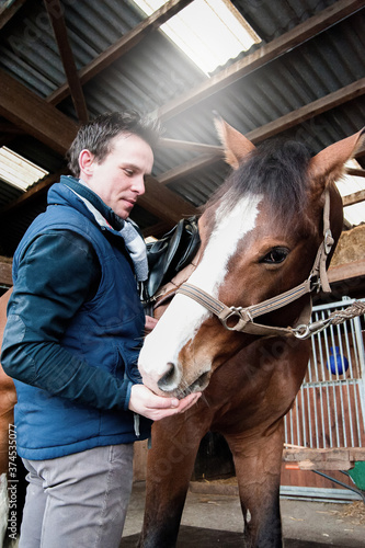 Portrait of a jockey standing by horse in stable