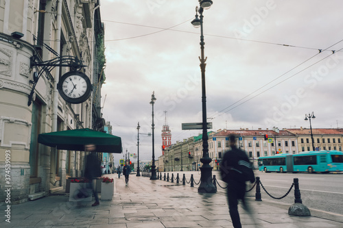 Street with clock and pedestrians in the early morning. Horizontal image.