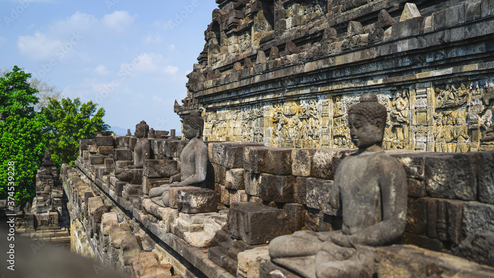 Naklejka premium Statue of sitting buddha at Borobudur Temple, spiritual stone sculpture, UNESCO world heritage site