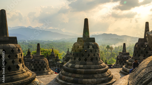 Glorious sunset at Borobudur Temple in East Java, Indonesia. Orange sky over the hills, green jungles and stupa, travel destination, UNESCO World Heritage Site