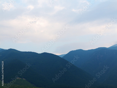 Fototapeta Naklejka Na Ścianę i Meble -  Evening mountain landscape at sunset. Silhouettes of the Pyrenees mountains and the cloudy sky are highlighted by the sun behind the mountains.