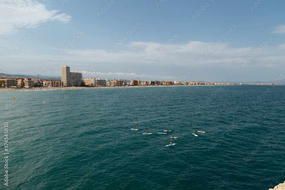 A group of people is practicing paddle surfing on the background of the sea city