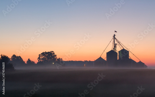 A midwest farm silhouetted at dawn