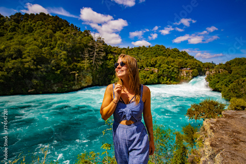 young woman in sunglasses in front of a waterfallw