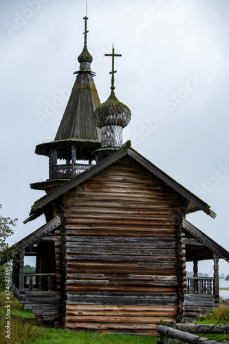 old wooden church on the island between trees in the rain