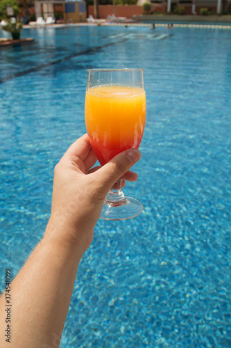 cocktail glass in hand against the pool background