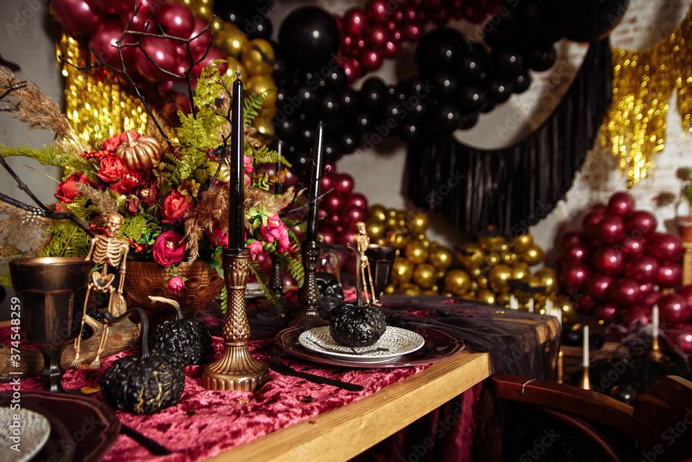 Halloween table decorated with some scary ornaments, such as a skull, a black bat or a carved pumpkin. Halloween Still Life decoration. Holiday decorations Halloween table decorated with some scary ornaments, such as a skull, a black bat or a carved pumpkin. Halloween Still Life decoration. Holiday decorations