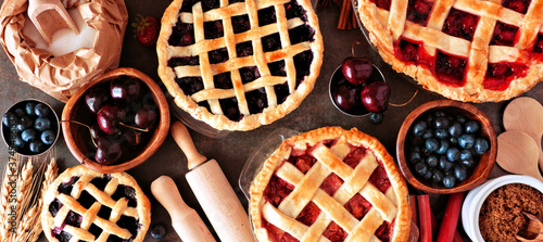 Baking scene with a variety of homemade fruit pies. Top view over a wood banner background. photo
