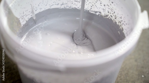 The white paint is mixed in a bucket with a drill. Drill paddle mixer on a bucket with white paint, DIY tools and accessory, banner