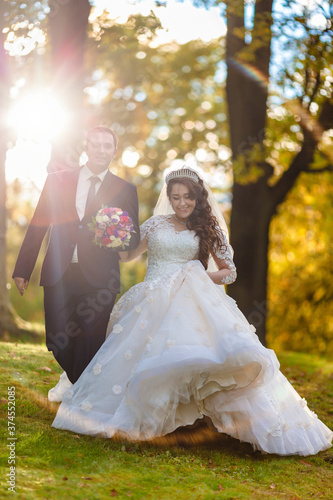 Newlyweds walk in the park and pose for a photographer