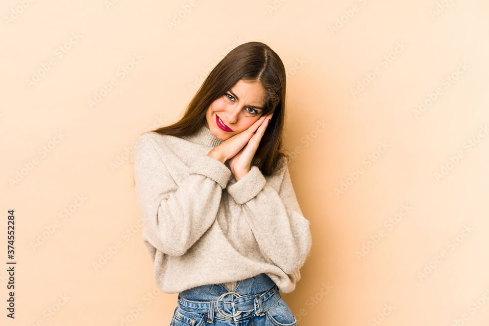 Young caucasian woman isolated en beige background yawning showing a tired gesture covering mouth with hand. Young caucasian woman isolated en beige background yawning showing a tired gesture covering mouth with hand.