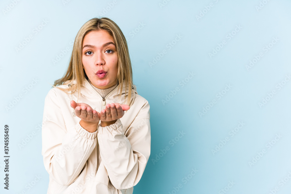 Young blonde caucasian woman isolated folding lips and holding palms to send air kiss. Young blonde caucasian woman isolated folding lips and holding palms to send air kiss.