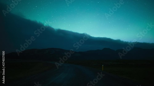 Aurora borealis over Icelandic country road and clouds timelapse photo