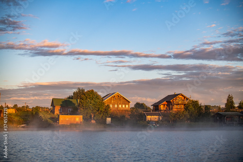 houses by the lake in a haze of fog at sunrise