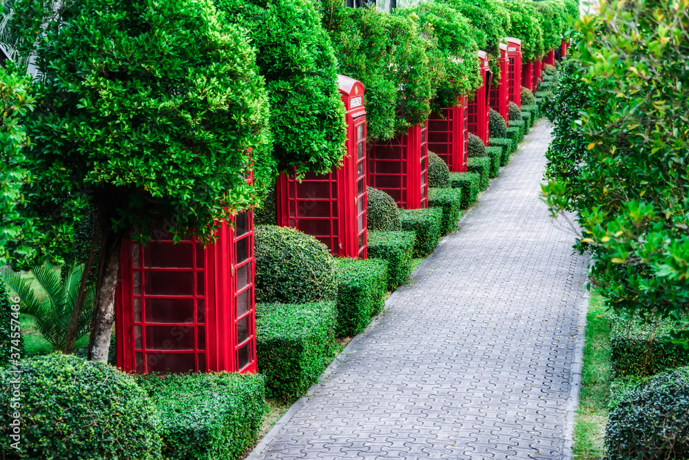 Obraz premium Alley in the tropical garden of Nong Nooch. Red telephone boxes. Thailand, Pattaya