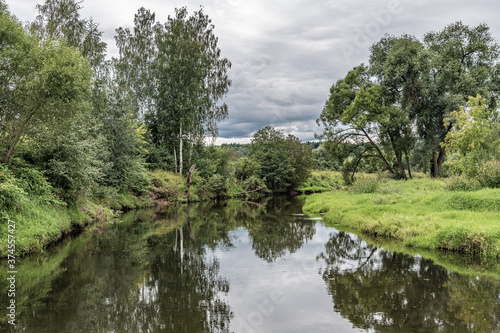 Trees are reflected in the dark waters of the river