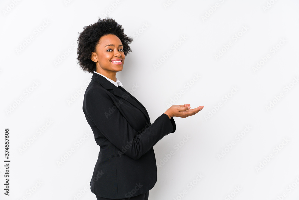 Middle aged african american business woman against a white background isolated holding a copy space on a palm. Middle aged african american business woman against a white background isolated holding a copy space on a palm.