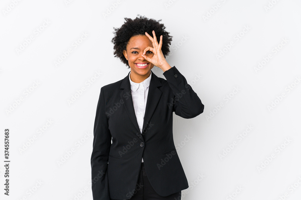 Middle aged african american business woman against a white background isolated excited keeping ok gesture on eye. Middle aged african american business woman against a white background isolated excited keeping ok gesture on eye.
