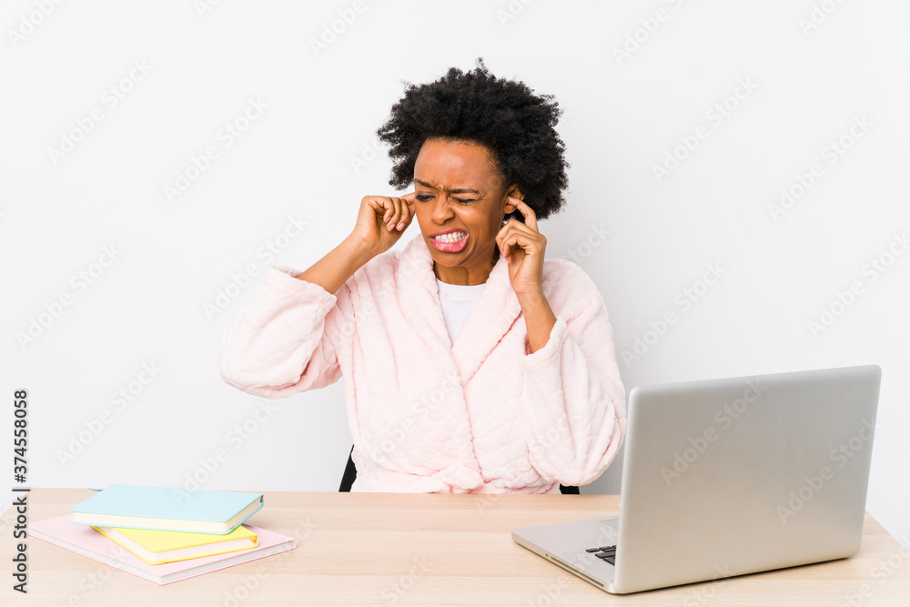 Middle aged african american woman working at home isolated covering ears with hands. Middle aged african american woman working at home isolated covering ears with hands.