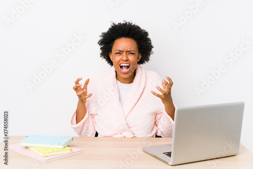 Middle aged african american woman working at home isolated screaming with rage.