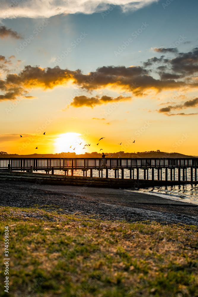 Fototapeta premium Woman on a pier at sunset