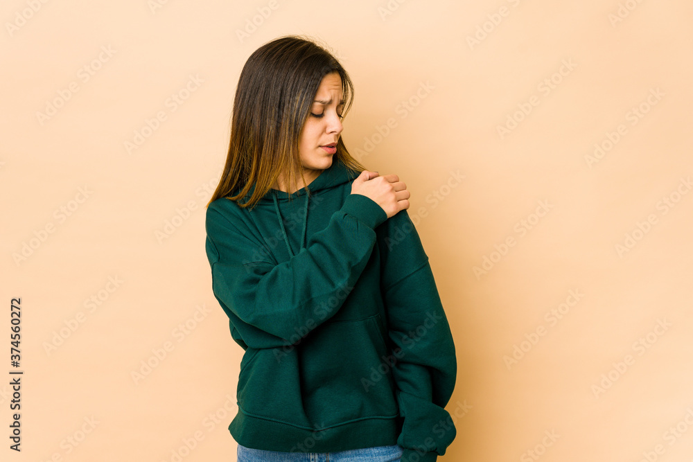 Young woman isolated on beige background having a shoulder pain. Young woman isolated on beige background having a shoulder pain.