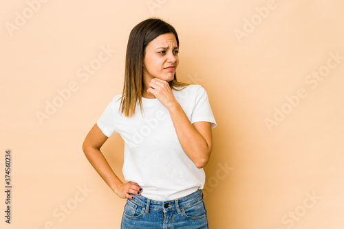 Young woman isolated on beige background suffers pain in throat due a virus or infection.