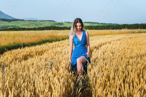 Beautiful woman in a blue dress in a wheat field against the sky. The concept of freedom and naturalness © Валентина Баранова