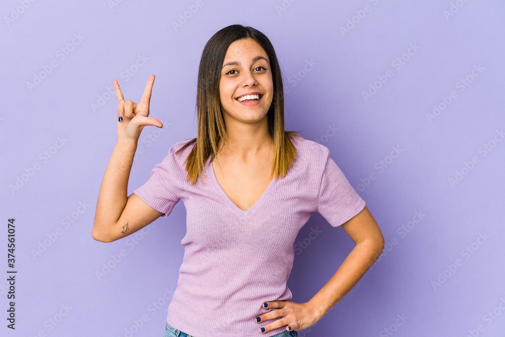 Young woman isolated on purple background showing a horns gesture as a revolution concept.