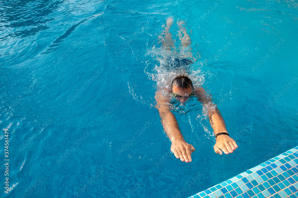 A young athlete swims to the side of the pool. Sports competitions in the pool. Healthy lifestyle concept. Swimmer