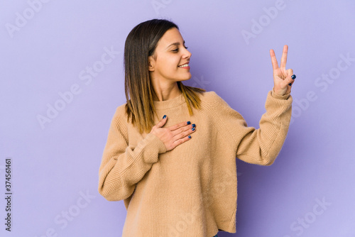 Young woman isolated on purple background taking an oath, putting hand on chest.
