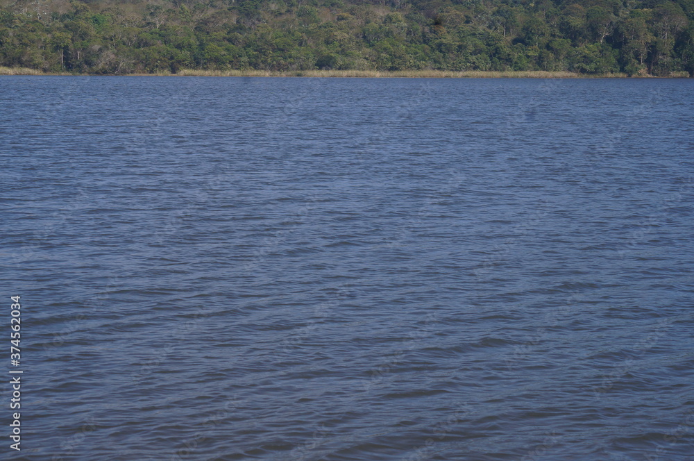 as águas de um belo e calmo lago azul com uma floresta ao fundo as águas de um belo e calmo lago azul com uma floresta ao fundo