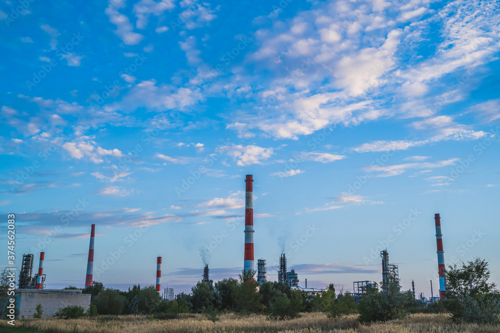 Factory pipes against the blue sky. Plant for the extraction and processing of oil. Horizontal photo