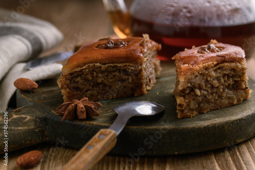 Baklava - an image on a natural wooden background of an Oriental dessert made of puff pastry with honey and nuts.
