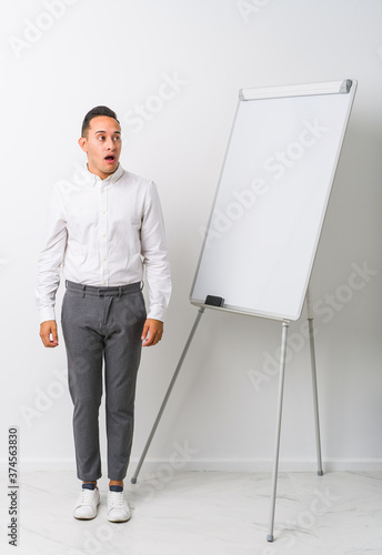 Young latin coaching man with a whiteboard isolated being shocked because of something she has seen.