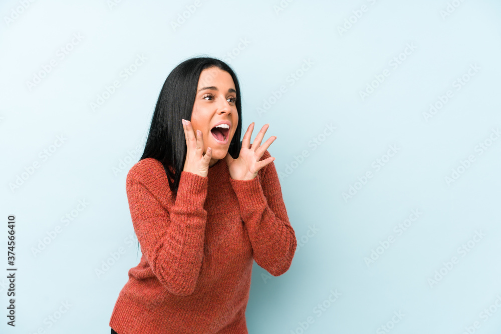 Young caucasian woman isolated on a blue background shouts loud, keeps eyes opened and hands tense. Young caucasian woman isolated on a blue background shouts loud, keeps eyes opened and hands tense.