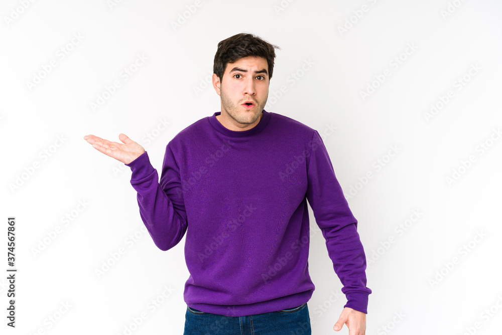 Fototapeta premium Young man isolated on white background impressed holding copy space on palm.