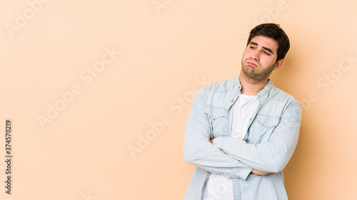 Young man isolated on beige background tired of a repetitive task.
