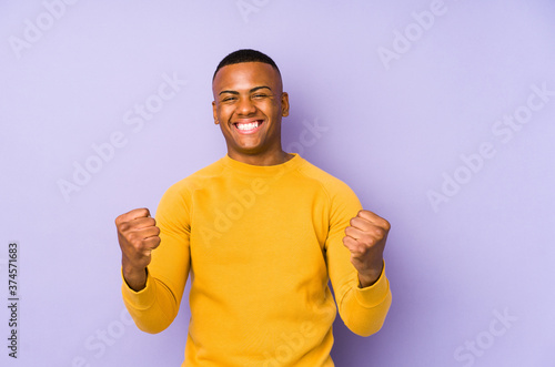 Young latin man isolated on purple background cheering carefree and excited. Victory concept.