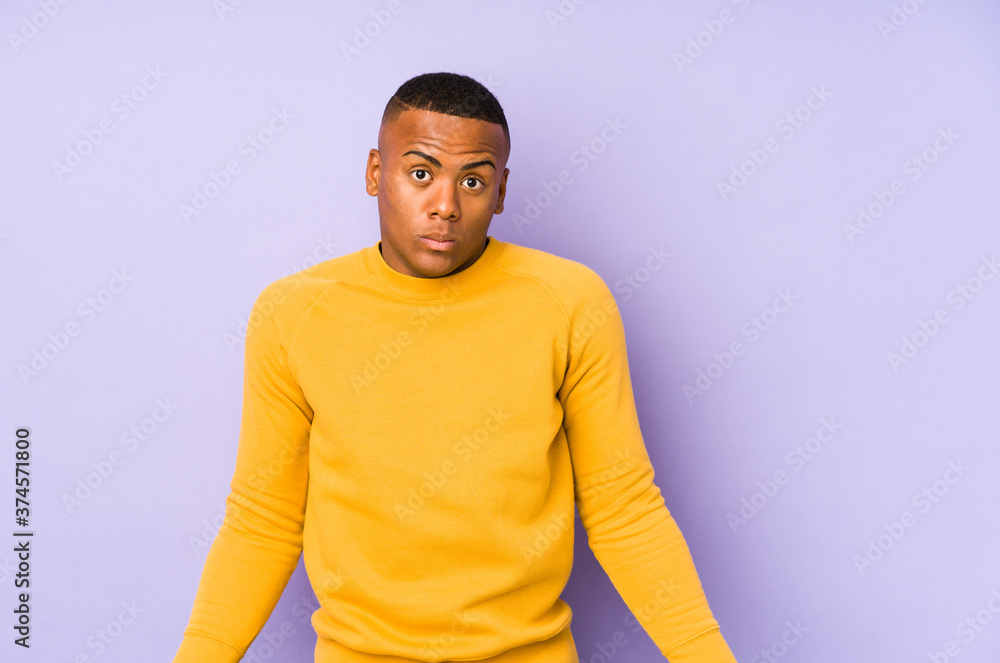 Young latin man isolated on purple background shrugs shoulders and open eyes confused. Young latin man isolated on purple background shrugs shoulders and open eyes confused.