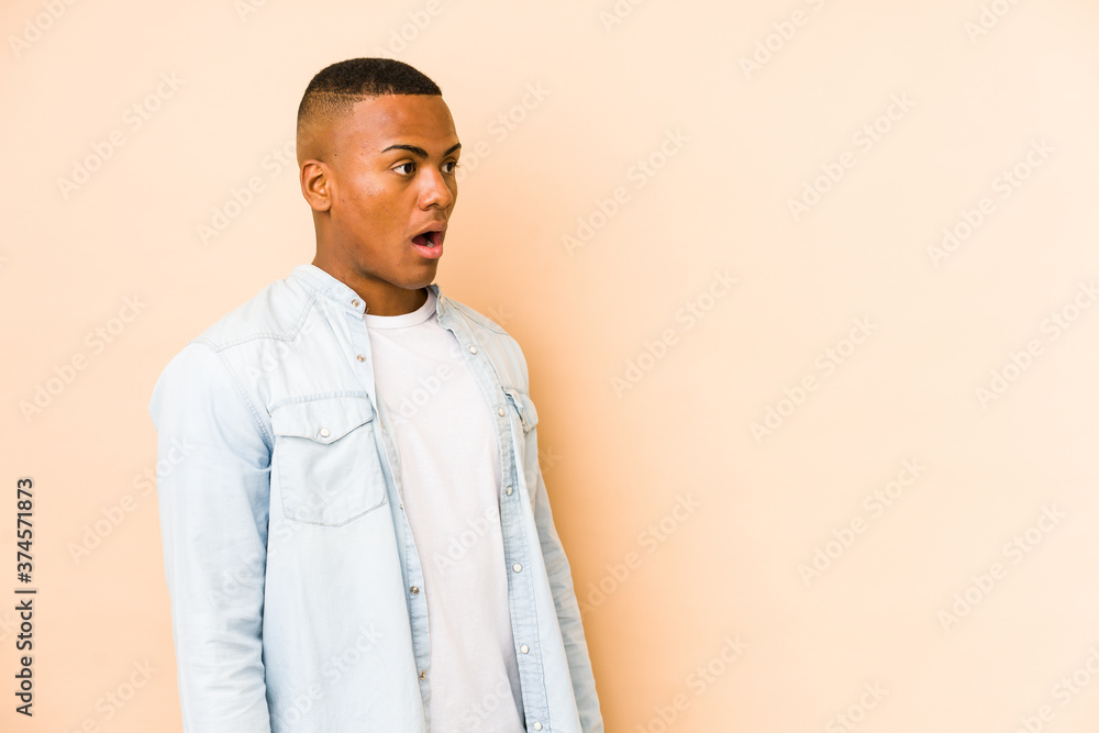 Young latin man isolated on beige background being shocked because of something she has seen. Young latin man isolated on beige background being shocked because of something she has seen.