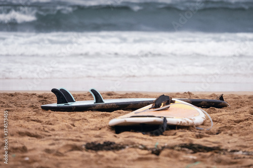 Surf board on a sandy beach by ocean.