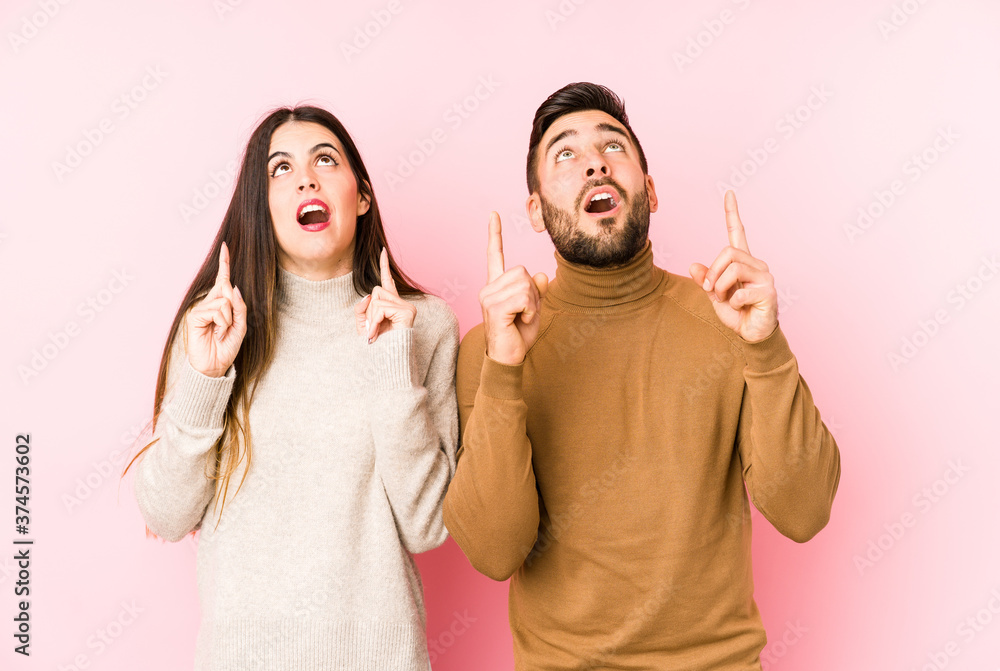 Young caucasian couple isolated pointing upside with opened mouth. Young caucasian couple isolated pointing upside with opened mouth.