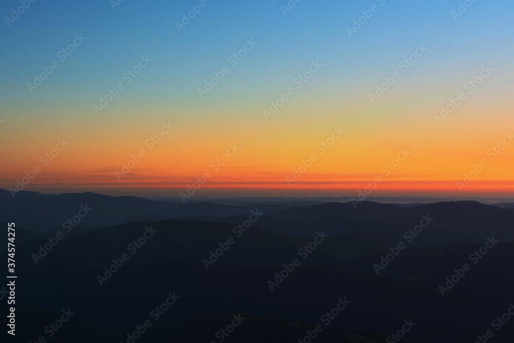 The first or last rays of the sun on a mountain pass. Morning and evening in nature. Colorful sunset and sunrise over the mountain hills. Carpathians in summer and autumn.