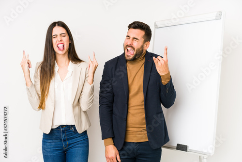 Young caucasian business couple isolated showing rock gesture with fingers