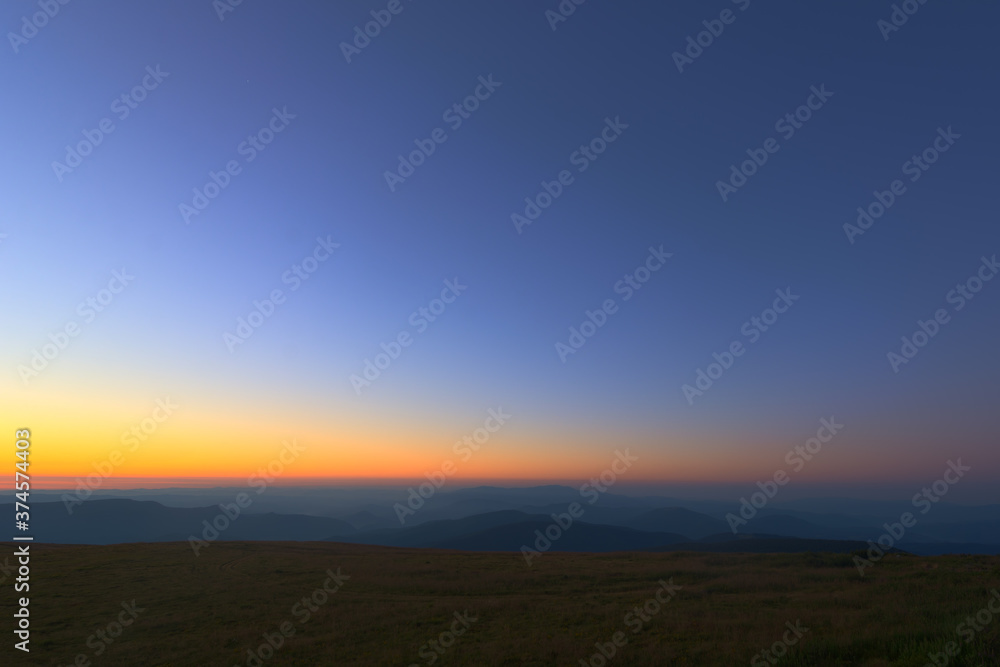 The first or last rays of the sun on a mountain pass. Morning and evening in nature. Colorful sunset and sunrise over the mountain hills. Carpathians in summer and autumn.