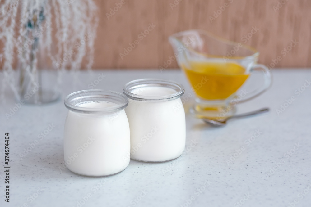 two glass jars with classic thermostat yoghurt and honey. two glass jars with classic thermostat yoghurt and honey.